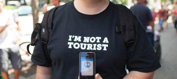 Man with t-shirt that says I am not a tourist with an iphone infront of him
