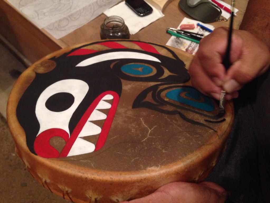 Tony Paul painting a killer whale on a drum at the Sechelt Nation Long House
