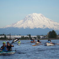 Team from the Seventy48 race kayaking on Commencement Bay with Mount Rainier in the background.